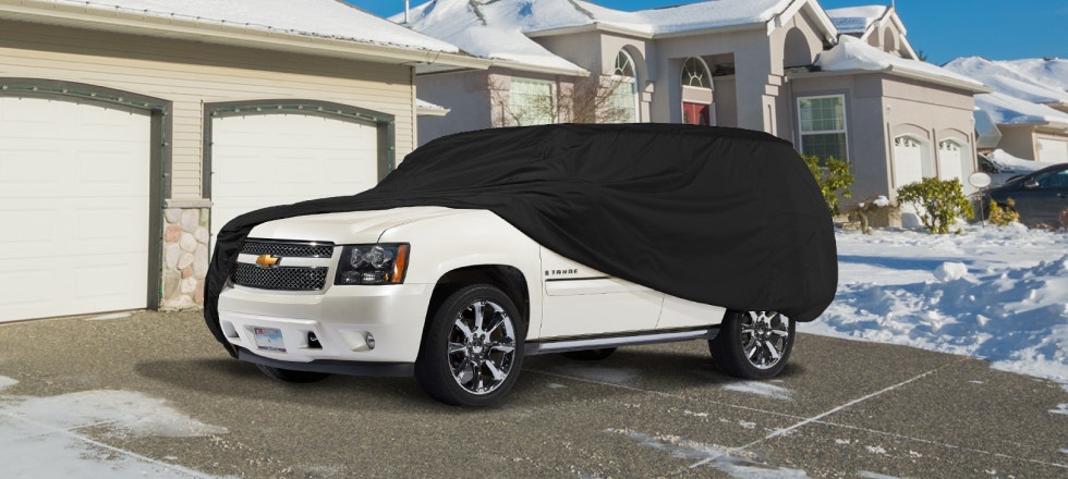 SUV with a black cover on a driveway during the winter