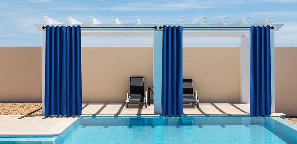 Blue outdoor curtains hanging next to a pool