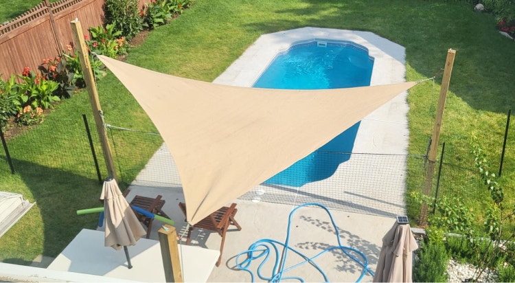 Triangular shade sail covering a patio near a pool