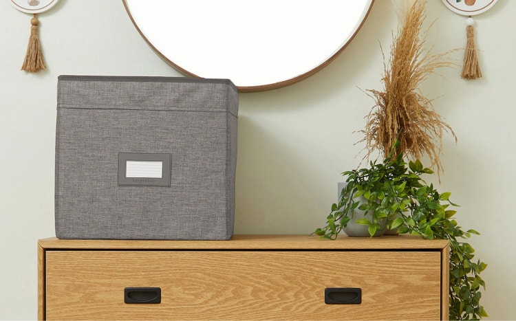 Grey storage bin sitting on a cabinet