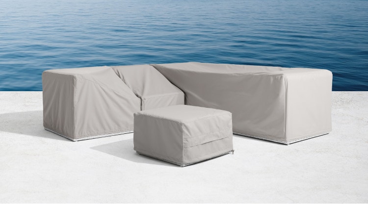 Outdoor sectional and ottoman with grey covers near a body of water