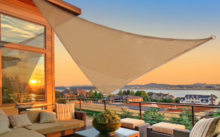 Tan triangular shade sail hanging over patio furniture